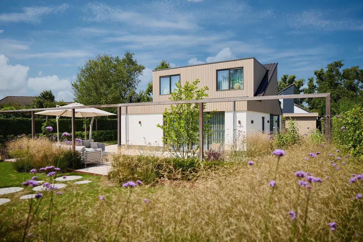 Een moderne woning met een losse bloemenweide en siergrassen ervoor.